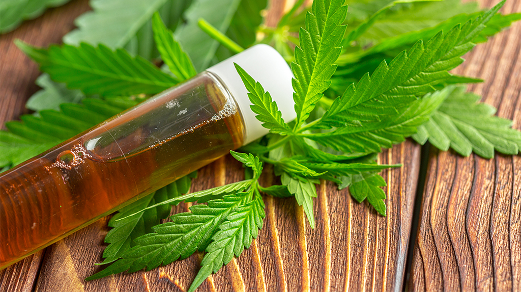 cannabis leaves and oil on wood table