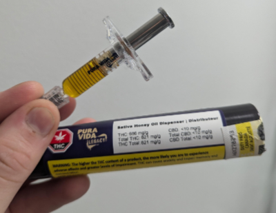 holding pura vida honey oil syringe